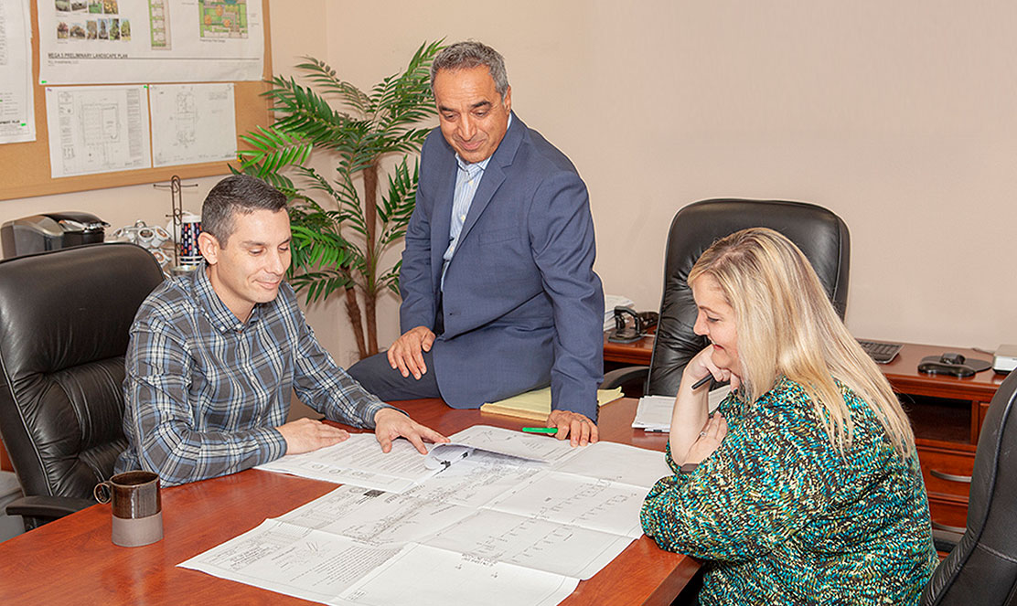 LDC senior engineer reviewing blueprints with surveying equipment